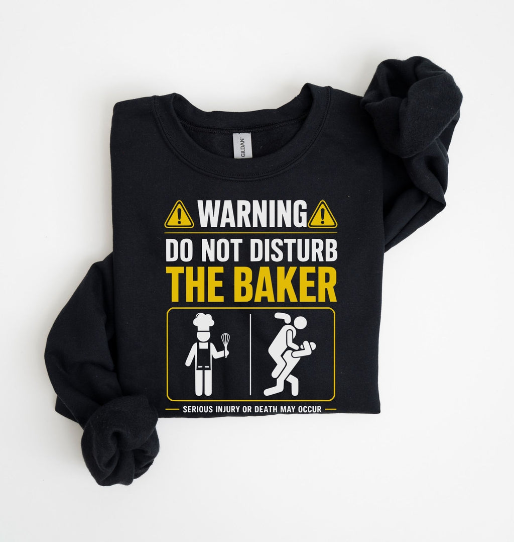 A black long-sleeve t-shirt with a humorous warning graphic printed on the front, laid flat on a white background.