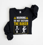 A black long-sleeve t-shirt with a humorous warning graphic printed on the front, laid flat on a white background.