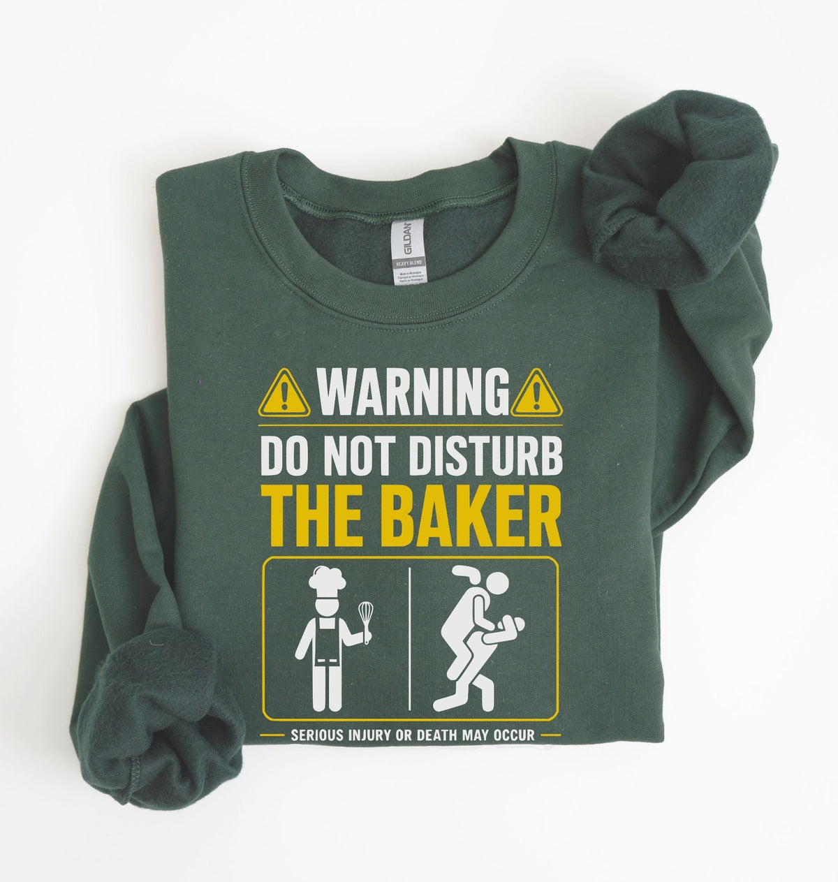A dark green crewneck sweatshirt with a humorous warning graphic printed on the front. The graphic reads 'WARNING DO NOT DISTURB THE BAKER' in white and yellow text, accompanied by stick-figure illustrations of a baker and a person crouching.