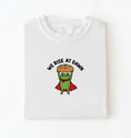 Flat lay of a white Funny We Rise At Dawn frog baker shirt featuring bread loaf graphic for sourdough enthusiasts on a white background 
