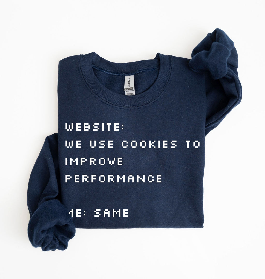 A navy blue crewneck sweatshirt with white pixelated text reading 'WEBSITE: WE USE COOKIES TO IMPROVE PERFORMANCE 4E: SAME', folded neatly on a white background.