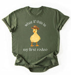 Flat lay of a Moss Military Green what if this is my first rodeo shirt brown funny cowboy duck t shirt western humor gift on a white background 