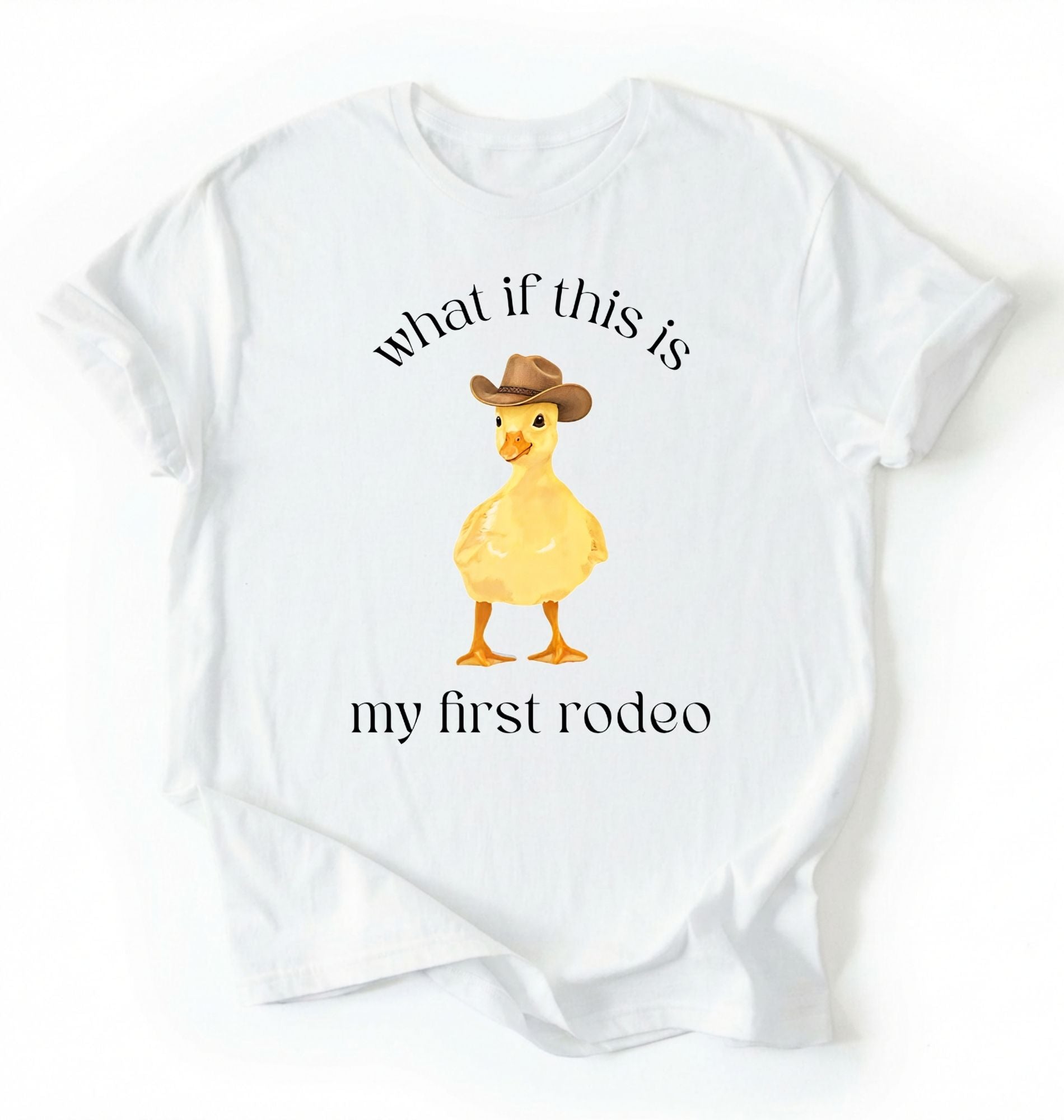 Flat lay of a White what if this is my first rodeo shirt brown funny cowboy duck t shirt western humor gift on a white background 