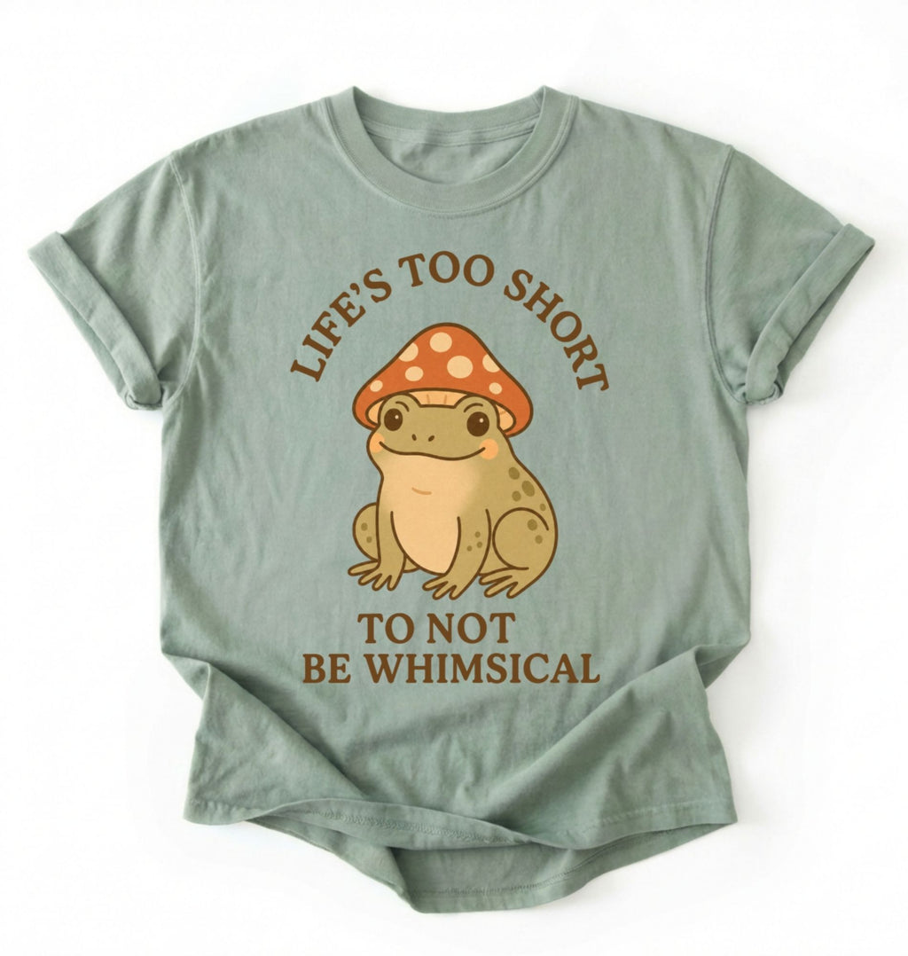 Flat lay of a bay whimsical frog shirt cream cute mushroom frog t shirt cottagecore aesthetic gift design on a white background 