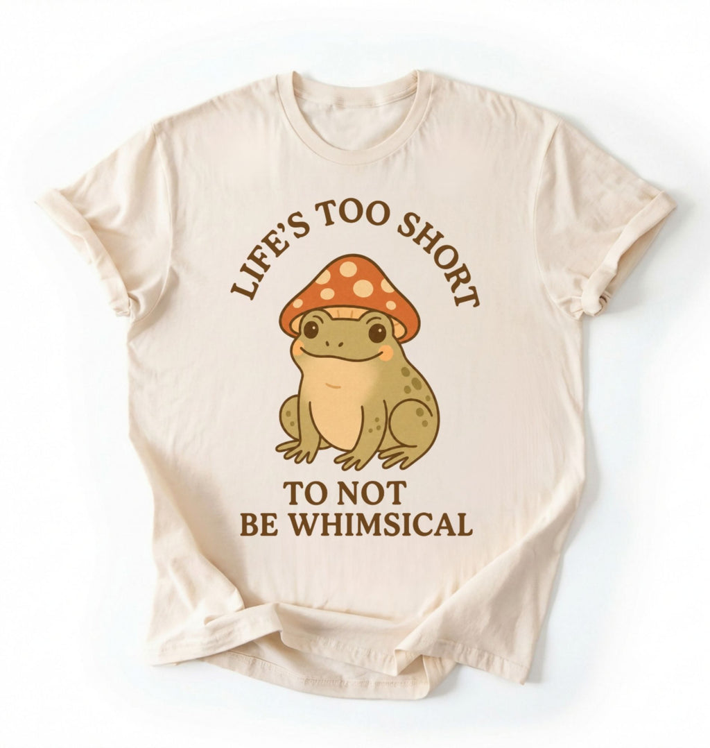 Flat lay of a natural whimsical frog shirt cream cute mushroom frog t shirt cottagecore aesthetic gift design on a white background 