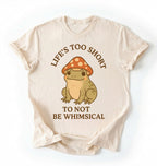 Flat lay of a natural whimsical frog shirt cream cute mushroom frog t shirt cottagecore aesthetic gift design on a white background 