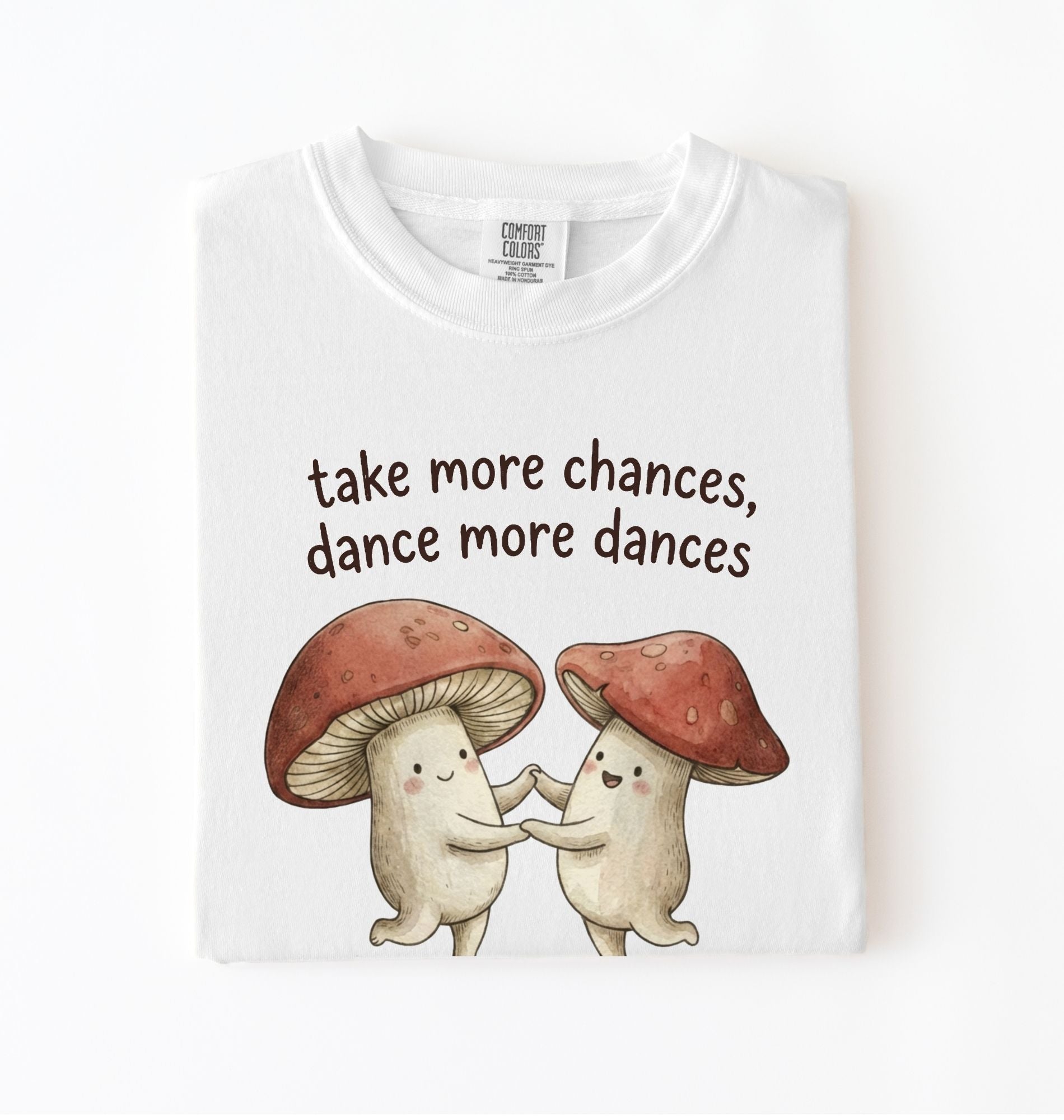White t-shirt with two dancing mushrooms and the phrase take more chances dance more dances, whimsical cottagecore gift tee