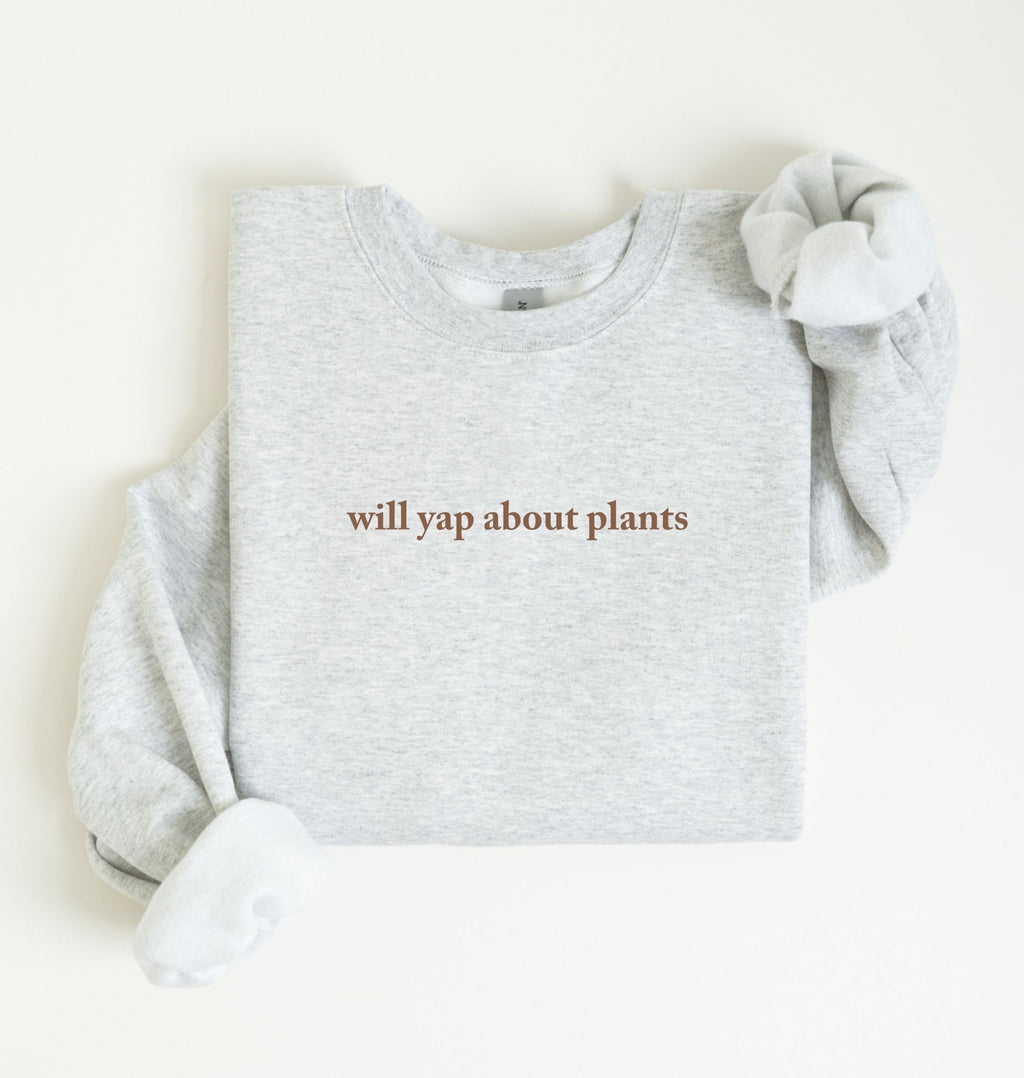 Flat lay of a ash cozy crewneck sweatshirt on a white background with text reading “Will yap about plants centered on the front  
