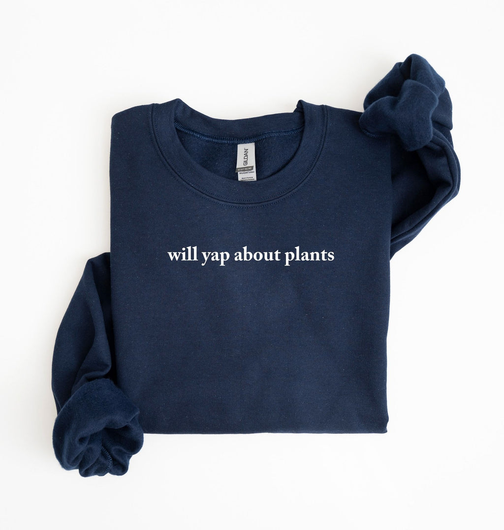 Flat lay of a navyblue cozy crewneck sweatshirt on a white background with text reading “Will yap about plants centered on the front  