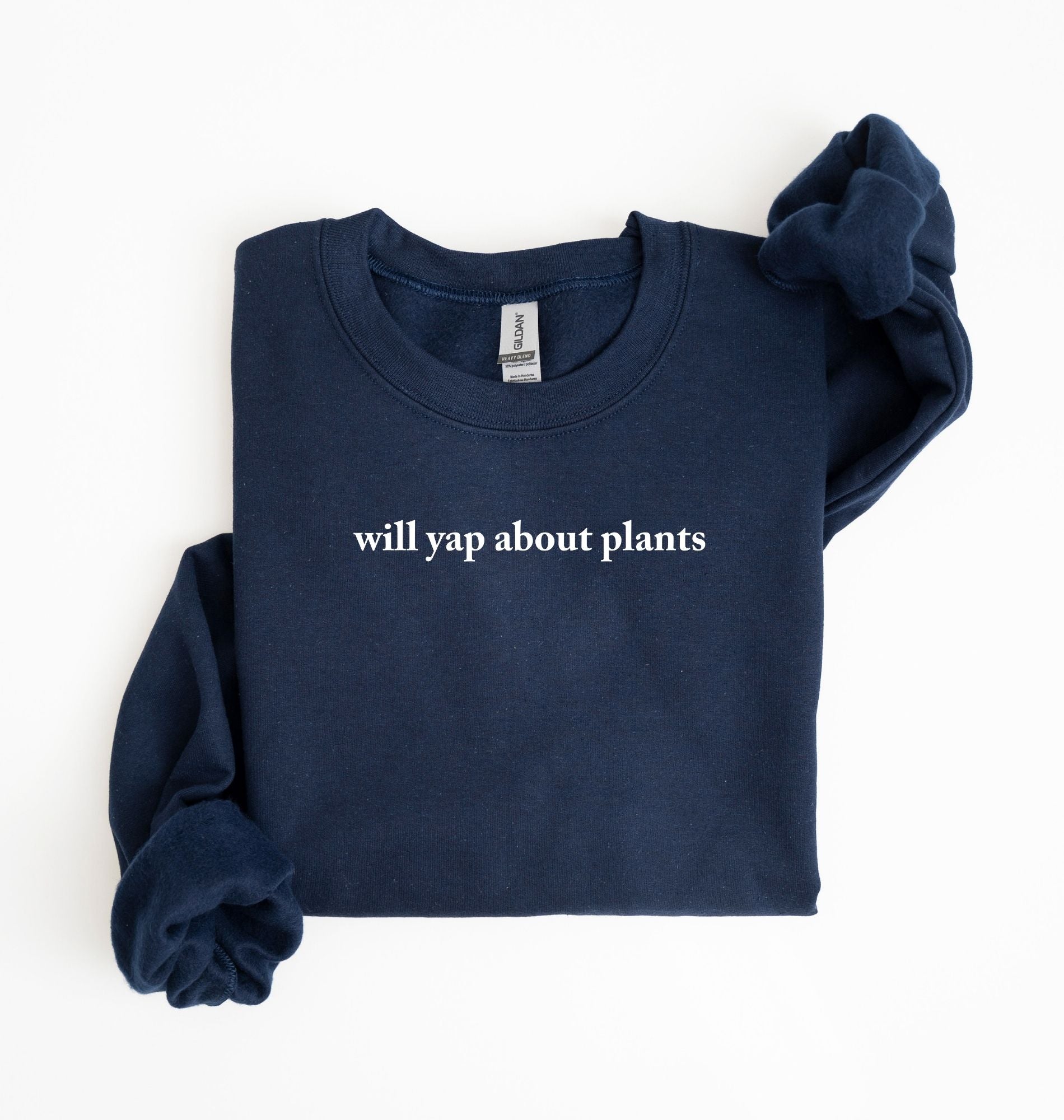 Flat lay of a navyblue cozy crewneck sweatshirt on a white background with text reading “Will yap about plants centered on the front  