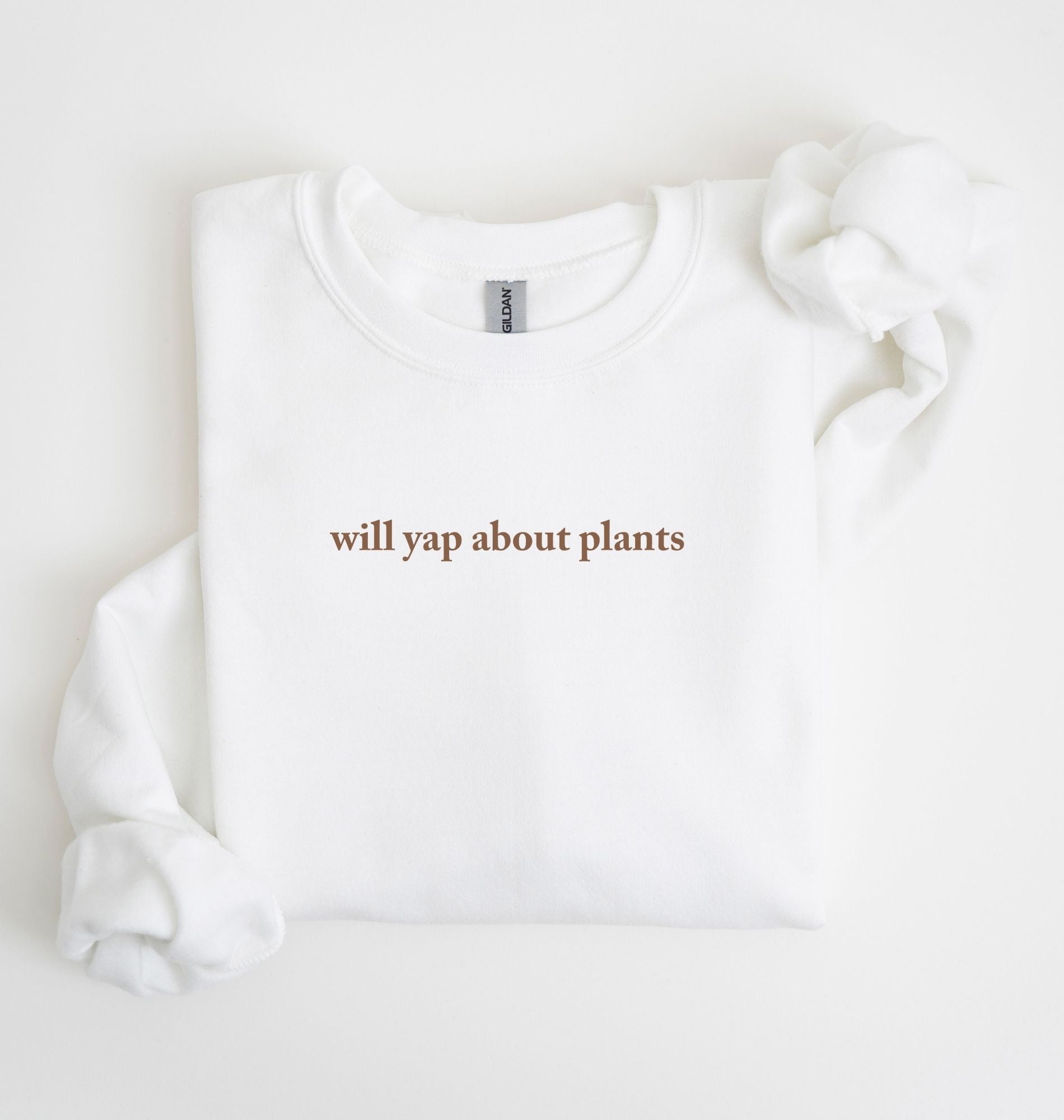 Flat lay of a white cozy crewneck sweatshirt on a white background with text reading “Will yap about plants centered on the front  