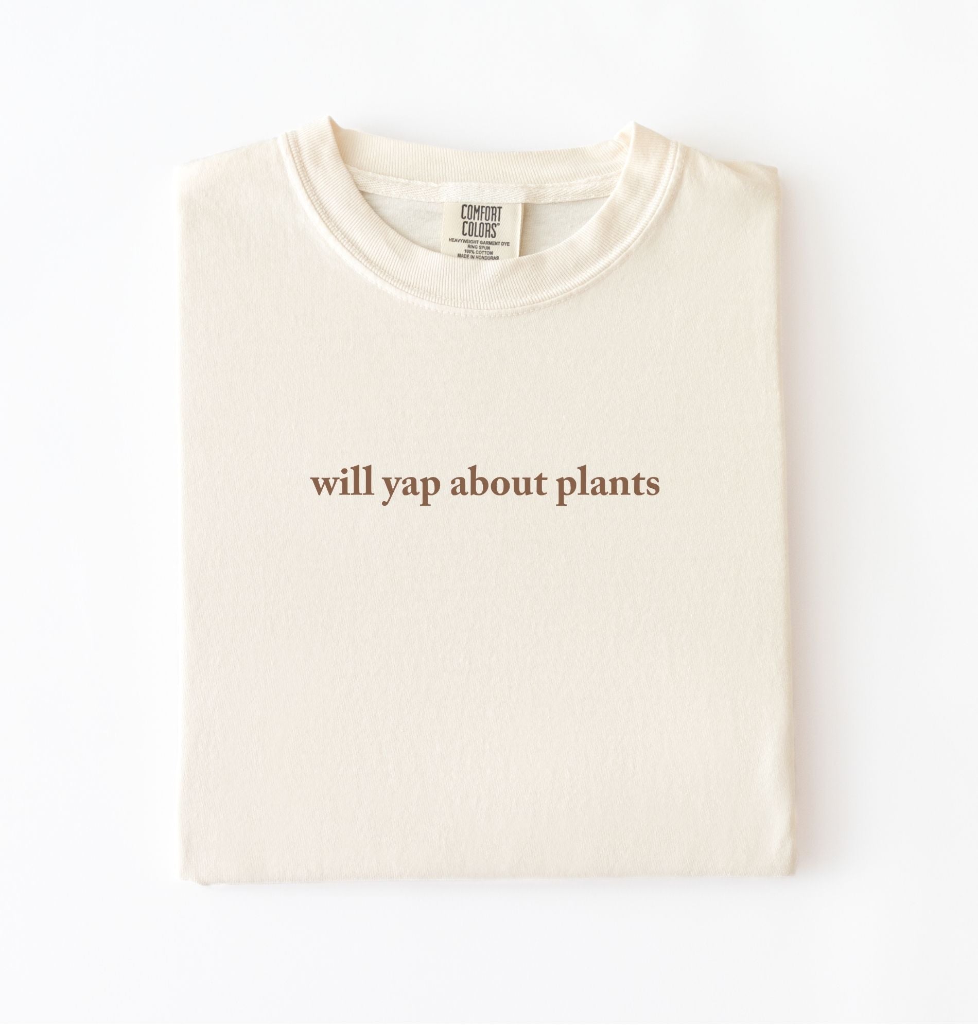 Flat lay of a ivory cozy crewneck t-shirt on a white background with text reading “Will yap about plants centered on the front 