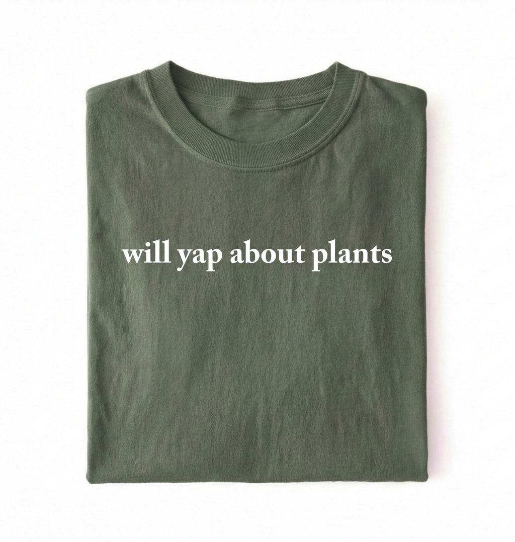 Flat lay of a moss cozy crewneck t-shirt on a white background with text reading “Will yap about plants centered on the front 