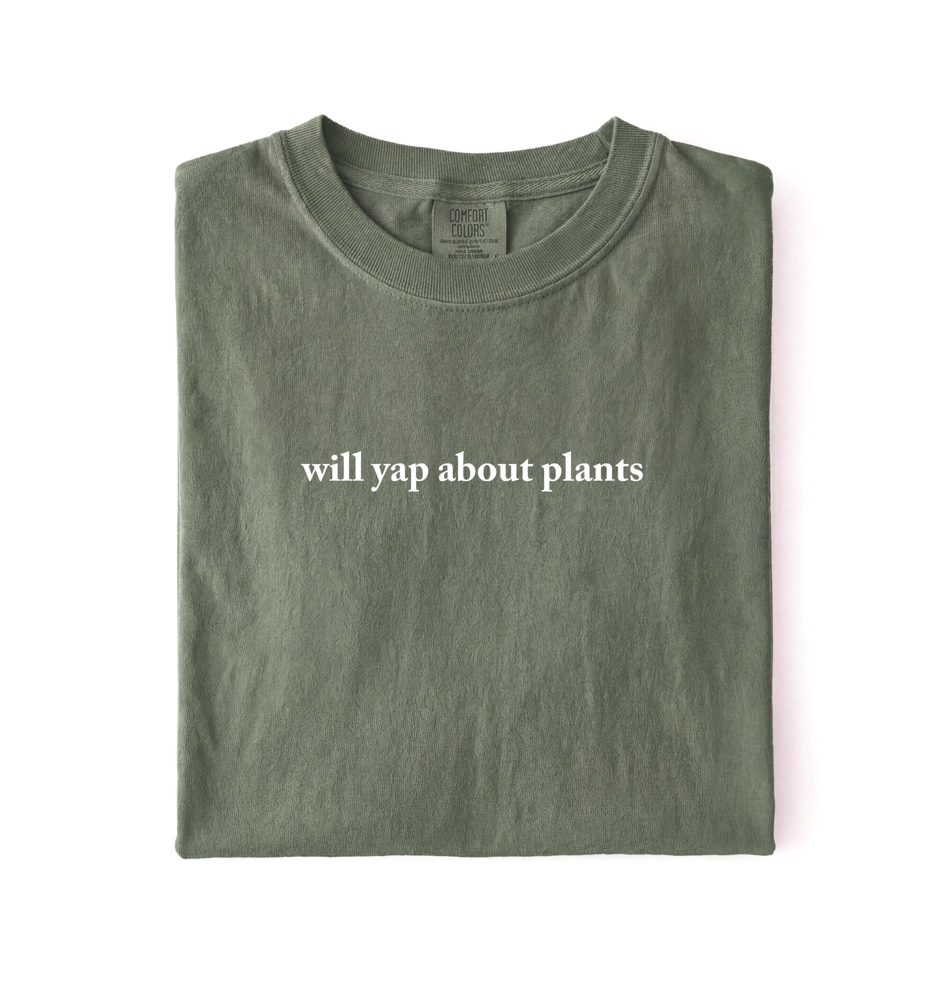 Flat lay of a moss cozy crewneck t-shirt on a white background with text reading “Will yap about plants centered on the front 