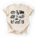 Flat lay of an Ivory t-shirt featuring detailed woodland animal illustrations including deer, fox, bear, owl, and raccoon on a white background 
