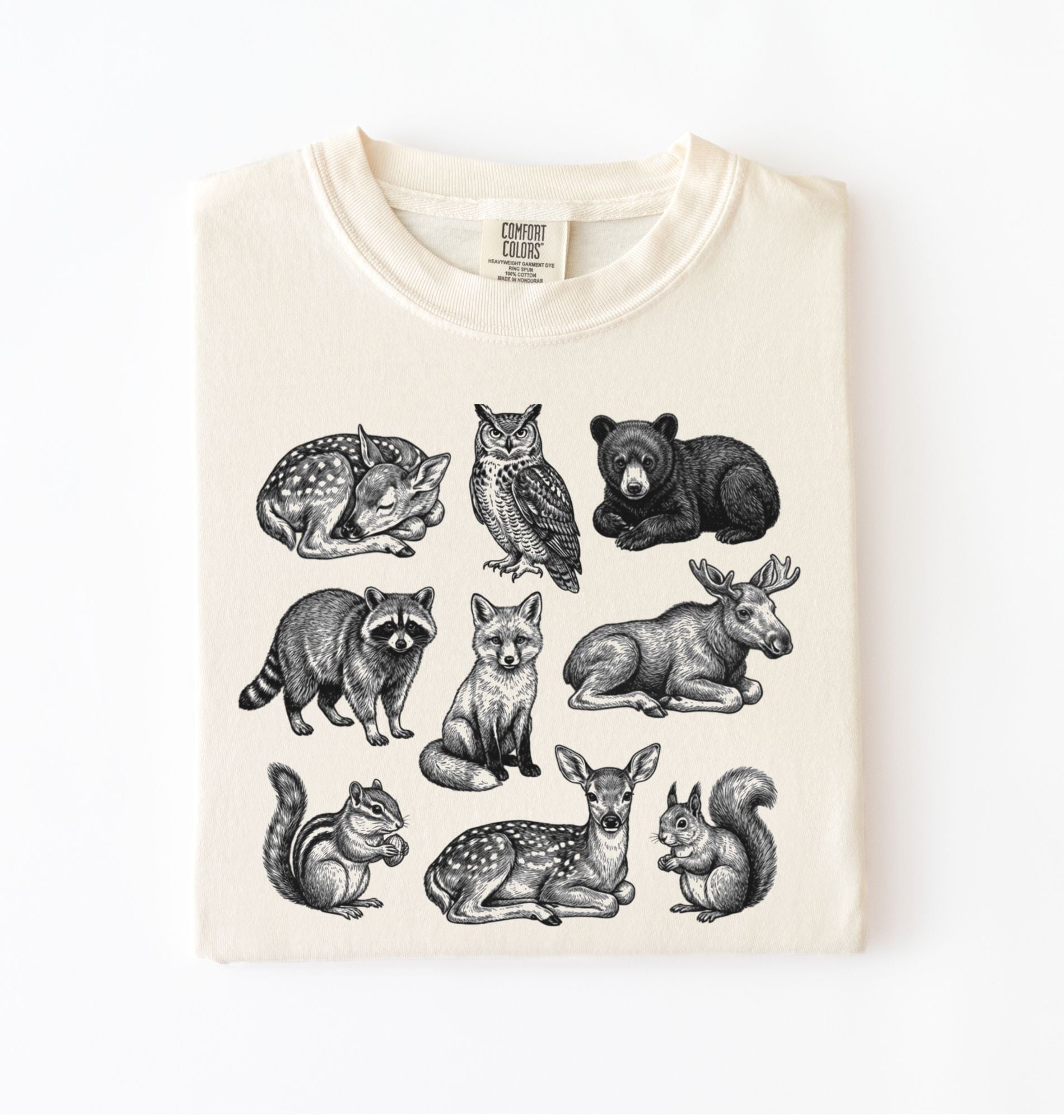 Ivory t-shirt featuring detailed woodland animal illustrations including deer, fox, bear, owl, and raccoon
