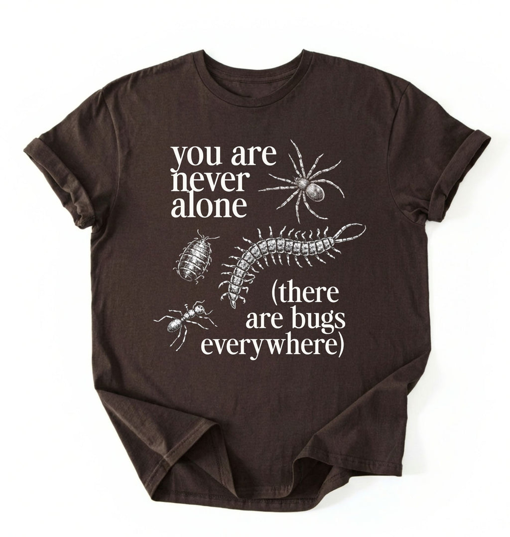 Flat lay of a darkchocolate t-shirt featuring illustrated insects including a spider and centipede with text reading “You Are Never Alone (there are bugs everywhere). Funny bug shirt insect illustrations design perfect gift for science lovers 
