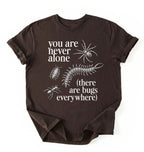 Flat lay of a darkchocolate t-shirt featuring illustrated insects including a spider and centipede with text reading “You Are Never Alone (there are bugs everywhere). Funny bug shirt insect illustrations design perfect gift for science lovers 