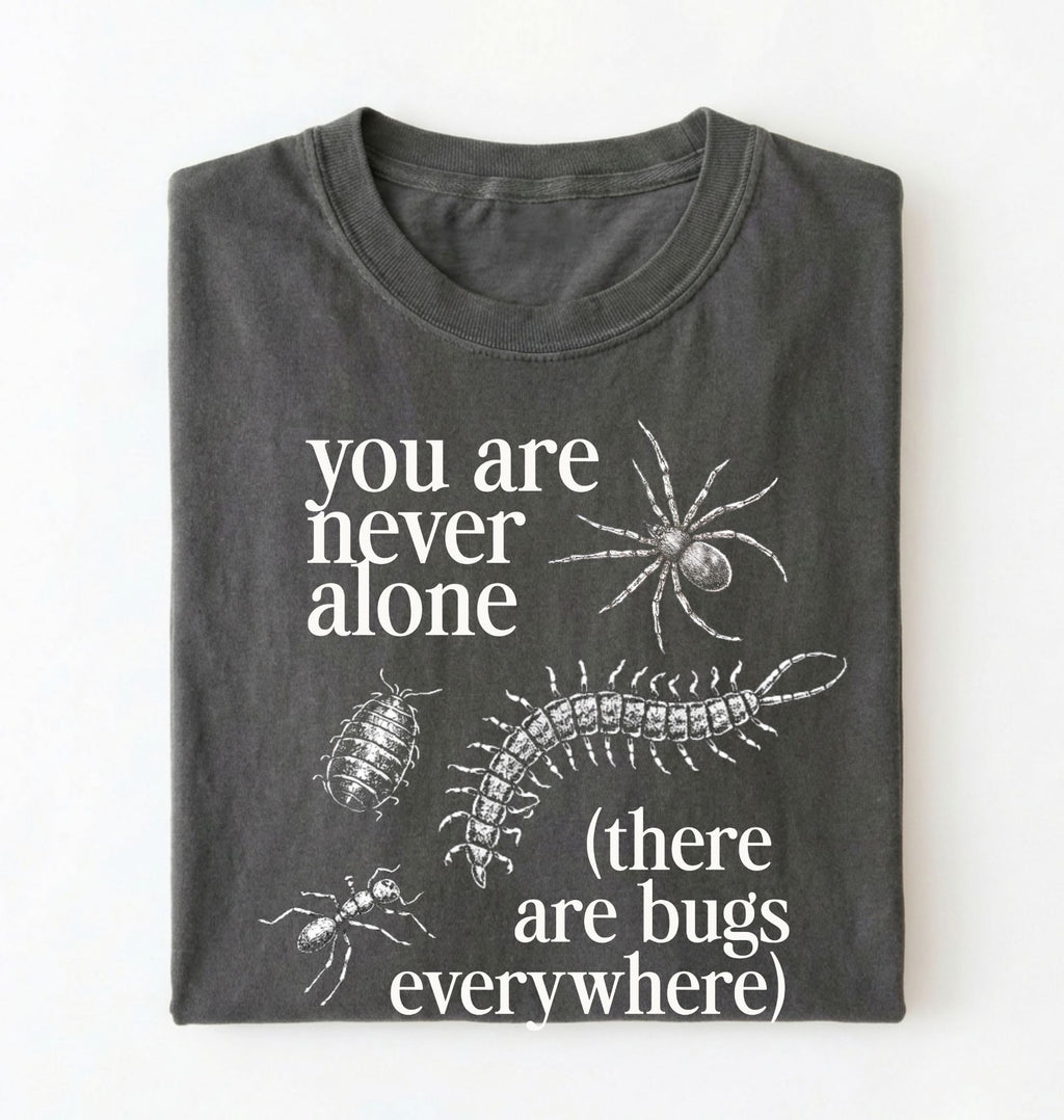 Flat lay of a pepper t-shirt featuring illustrated insects including a spider and centipede with text reading “You Are Never Alone (there are bugs everywhere). Funny bug shirt insect illustrations design perfect gift for science lovers 